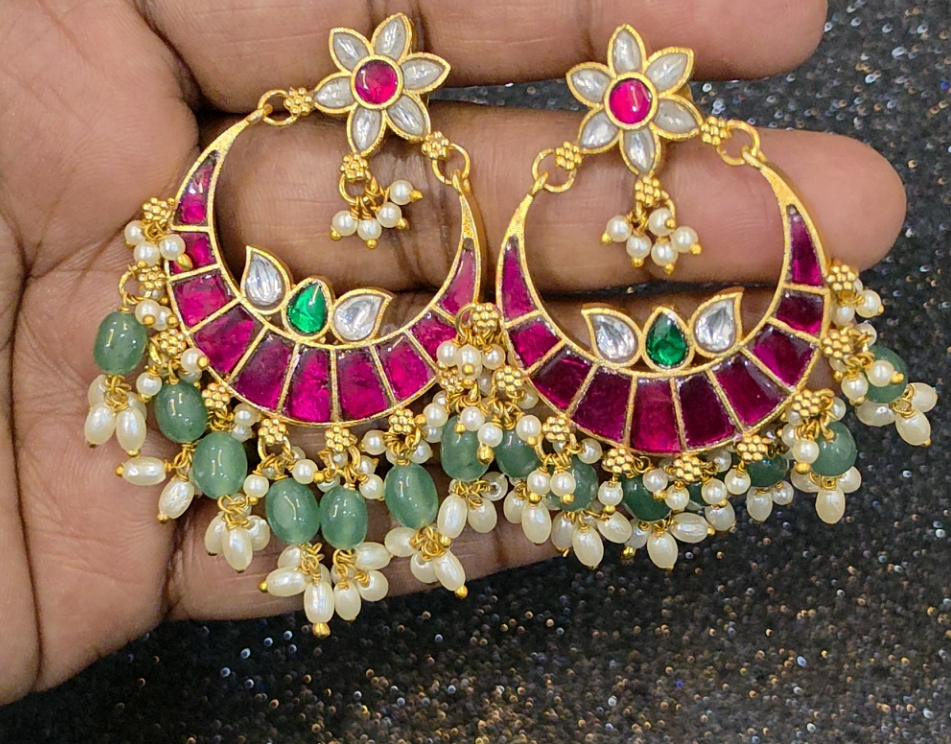 Jadau Kundan earrings with ruby-pink, emerald-green and white stones, gold-tone detailing, and pearl and green bead danglers.