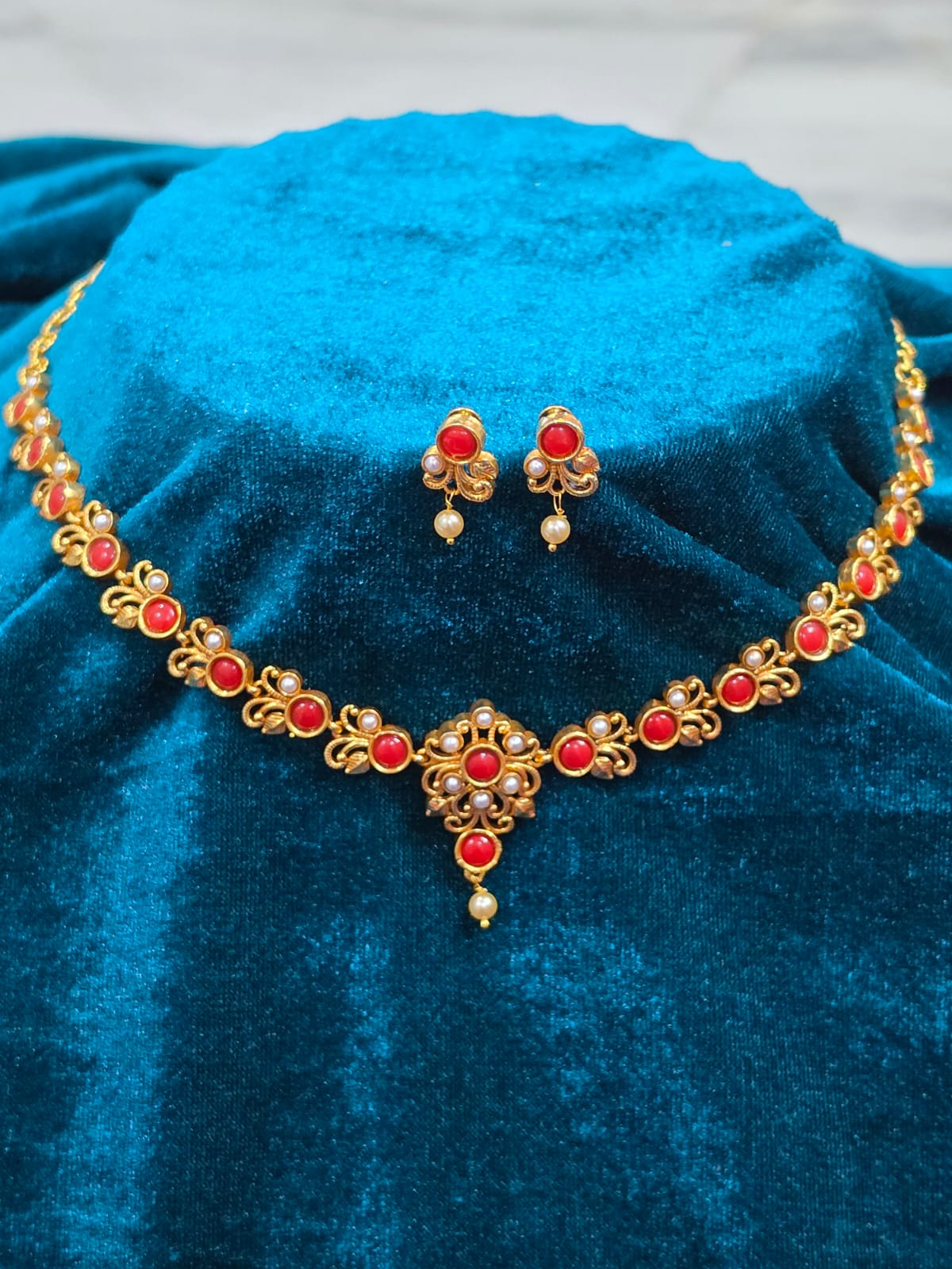 Pure Panchaloham coral and pearl jewellery set featuring a gold-toned necklace with red coral stones, pearl accents, floral detailing, and matching drop earrings